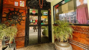 A hotel entrance with a black ornate door, a ship's wheel decoration, and potted plants. - Kathmandu Eco (Kathmandu)