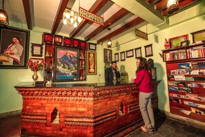 A reception desk with framed certificates, a cash register, and a bookshelf with various items. - Kathmandu Eco (Kathmandu)