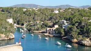 Un pueblo costero con barcos amarrados a lo largo del agua, rodeado de vegetación y edificios.