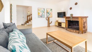 Una sala de estar con sofá, mesa de centro, chimenea y obras de arte en la pared.