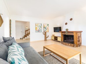 Ein Wohnzimmer mit Sofa, Couchtisch, Kamin und Bildern an der Wand.