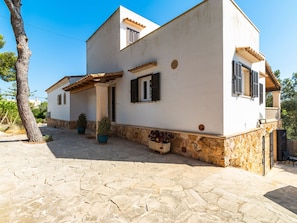 Ein zweigeschossiges Haus mit Steinfundament, einer gefliesten Terrasse und Blumentöpfen.