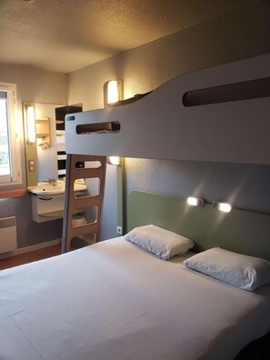 A bunk bed with a ladder, a bedside table, a mirror, and wall-mounted lights.