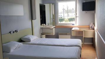 Habitación de hotel con dos camas, ventana, escritorio, espejo y televisión.