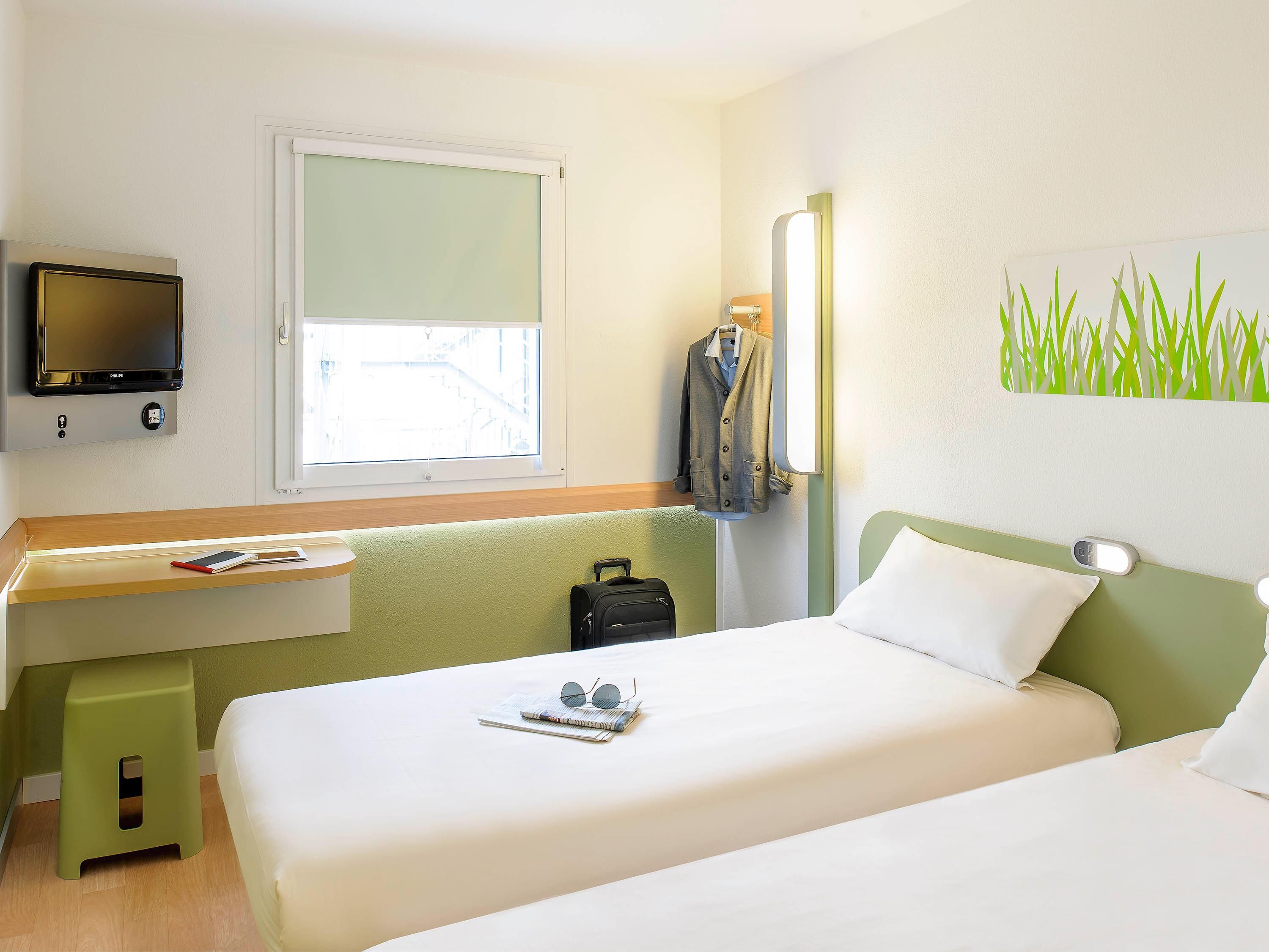 Une chambre d’hôtel avec un lit, une table de chevet, une télévision, une fenêtre et un tableau.