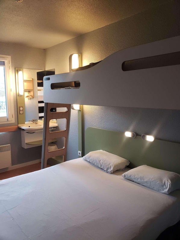 A bunk bed with a ladder, a bedside table, a mirror, and wall-mounted lights.