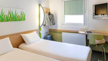 Een hotelkamer met twee bedden, een bureau met een computer, een televisie en een raam.