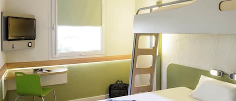Ein Hotelzimmer mit Etagenbett, Schreibtisch mit Stuhl, Fernseher und Fenster.