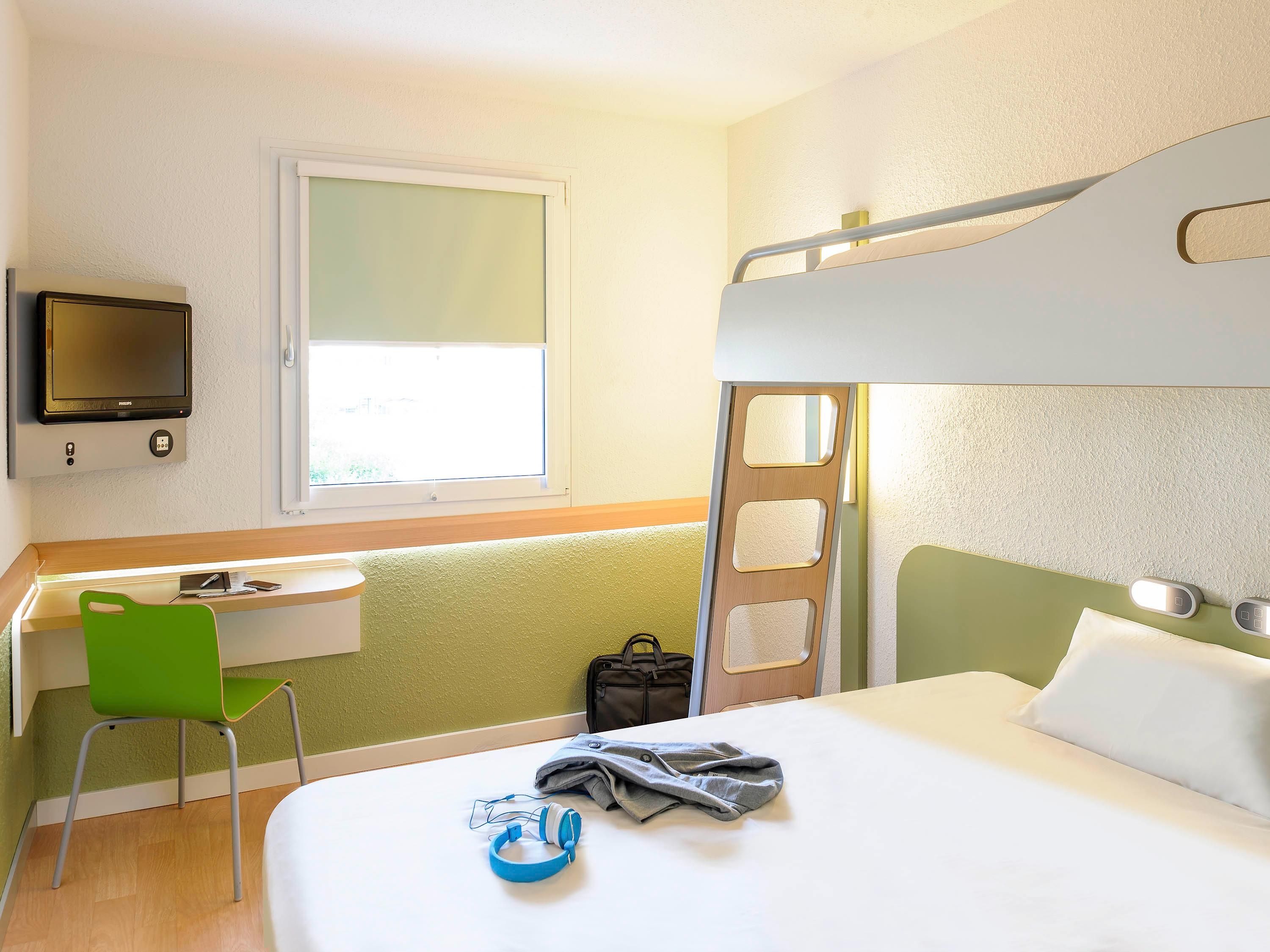 Een stapelbed met een bureau en stoel, een televisie en een raam.