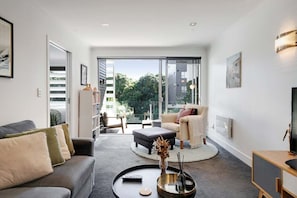 A modern living room with a sofa, armchair, and a round coffee table. - Comfortable city fringe Apt Near Basque Park (Eden Terrace)