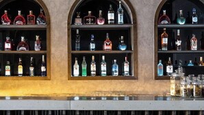 A bar with shelves of liquor bottles, a green plant wall, and a metal grill below. - The Leaf Boutique Hotel (Da Nang)