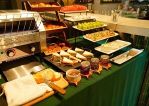 Monipuolinen buffet, jossa on tarjolla erilaisia ruokia, kuten voileipiä, hedelmiä ja lisukkeita.