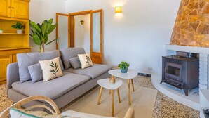 Una sala de estar con sofá, una mesita, un espejo, chimenea de piedra y un aparador de madera.