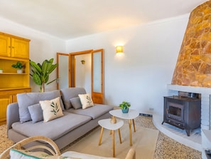 Ein Wohnzimmer mit einer Couch, einem kleinen Tisch, einem Spiegel, einem Kamin aus Stein und einer Holzkommode.