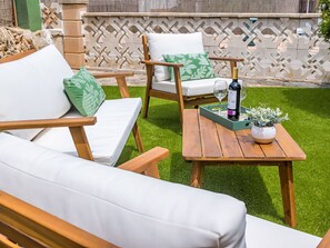 Eine Terrasse mit Holzmöbeln, einem Tisch mit Flasche und Gläsern sowie einer kleinen Pflanze.