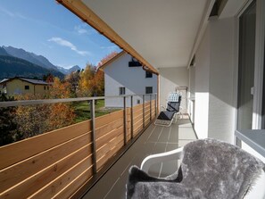 A balcony with a view of mountains, a wooden fence, and a chair. - FURTÜNADA, (Scuol) by Interhome (Scuol)