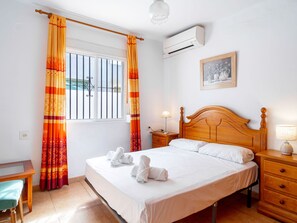 Une chambre d’hôtel avec un lit, des tables de chevet, un bureau et une fenêtre avec des rideaux.
