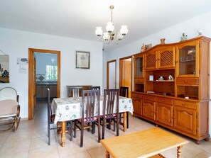 Ein Essbereich mit einem Tisch für vier Personen, einem Holzschrank mit Glastüren und einer Pendelleuchte.