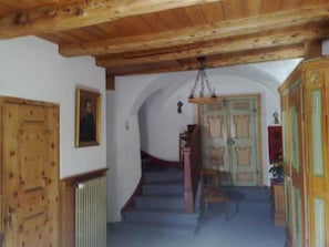 Eine Holztreppe führt zu einer Zwischenebene mit einer Tür und einem Heizkörper.