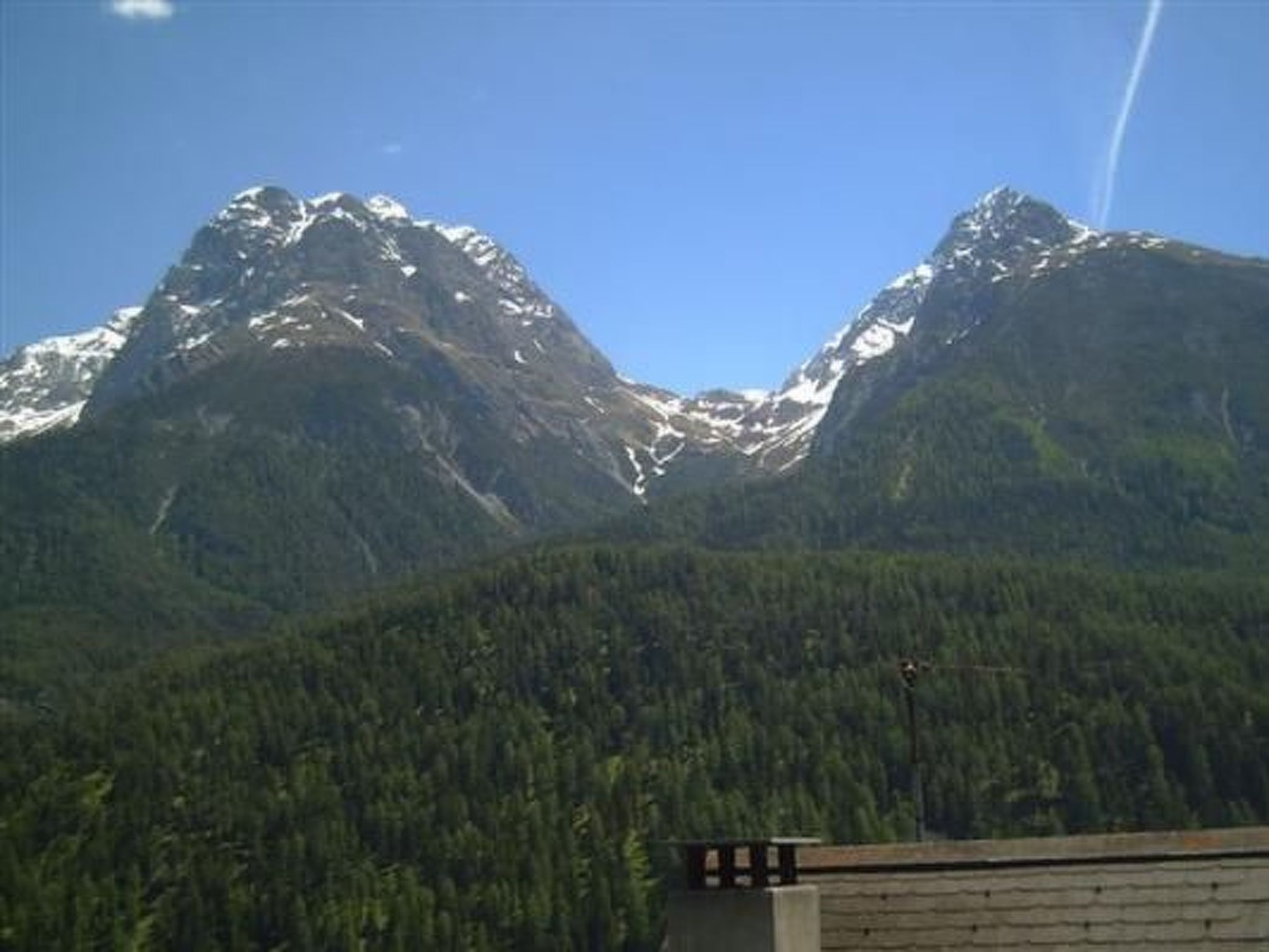 A mountain range with snow-capped peaks and dense forested valley.