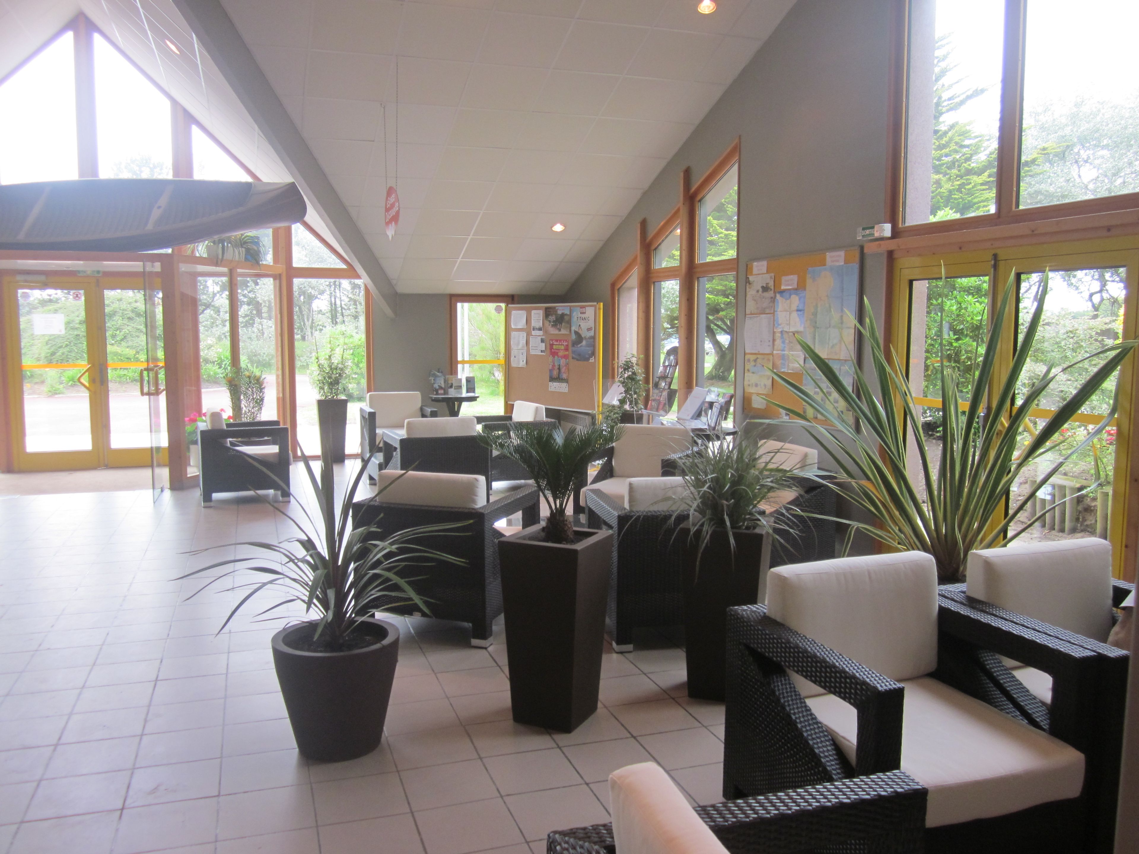 A spacious lobby with large windows, comfortable seating areas, and potted plants.