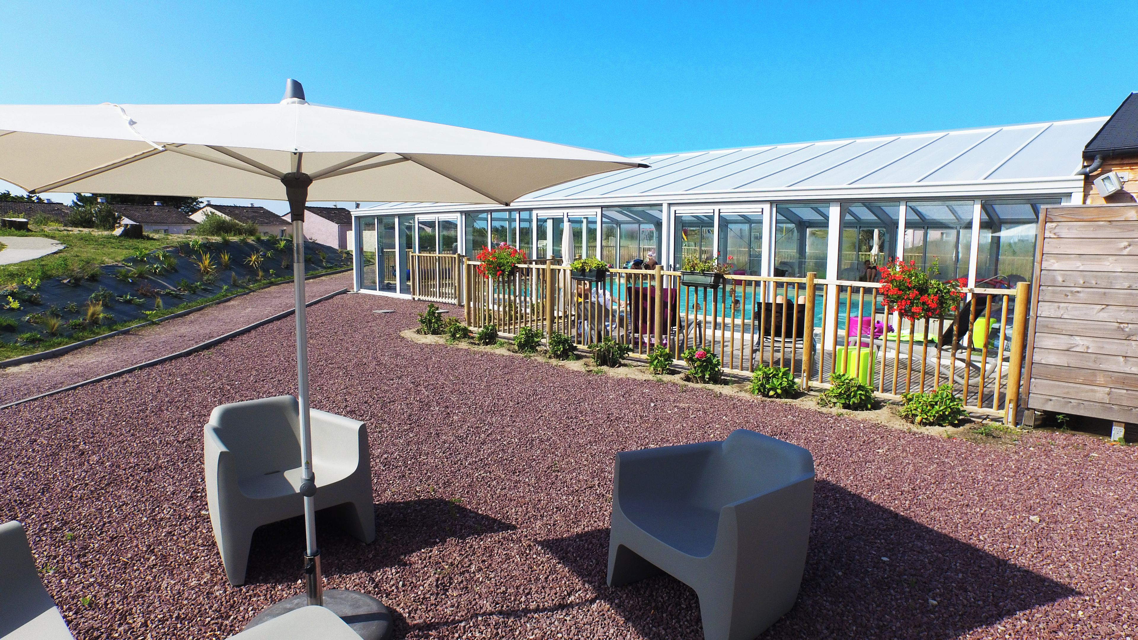 A patio with outdoor seating, a pool, and a greenhouse structure.