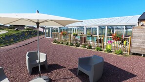 A patio with outdoor seating, a pool, and a greenhouse structure.