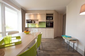 Une cuisine moderne avec un coin repas, comprenant une table avec des chaises, un banc et une fenêtre avec des rideaux.