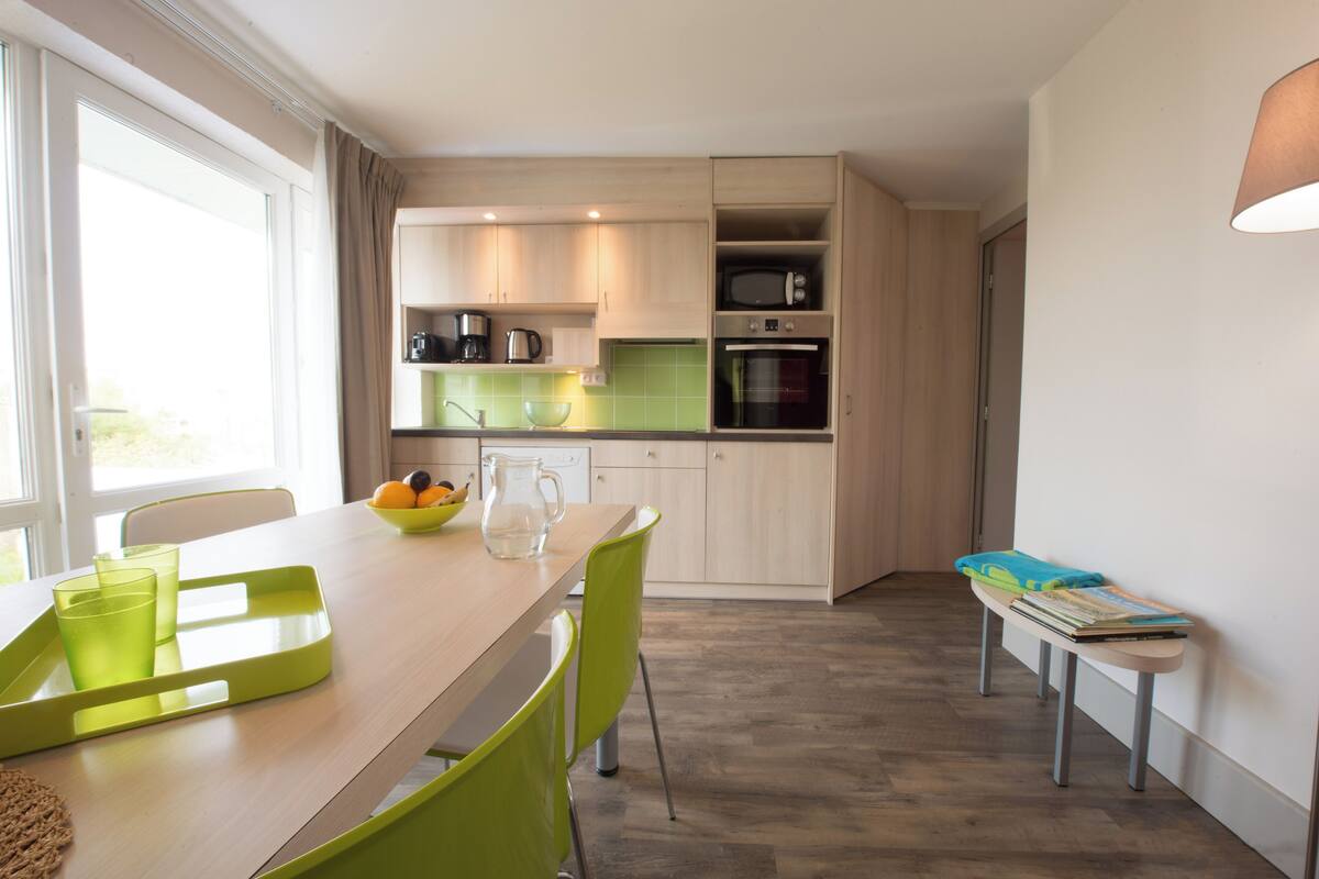 Une cuisine moderne avec un coin repas, comprenant une table avec des chaises, un banc et une fenêtre avec des rideaux.
