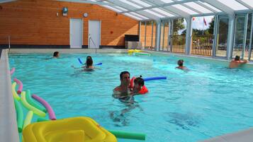Une piscine intérieure avec des murs en bois, un toit abrité et de grandes fenêtres en verre transparent.