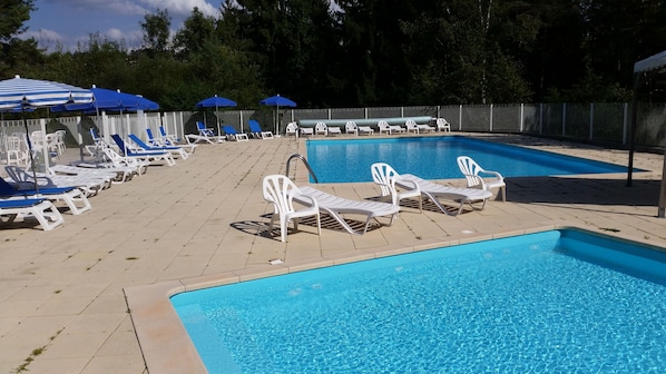 A pool area with multiple lounge chairs and umbrellas.
