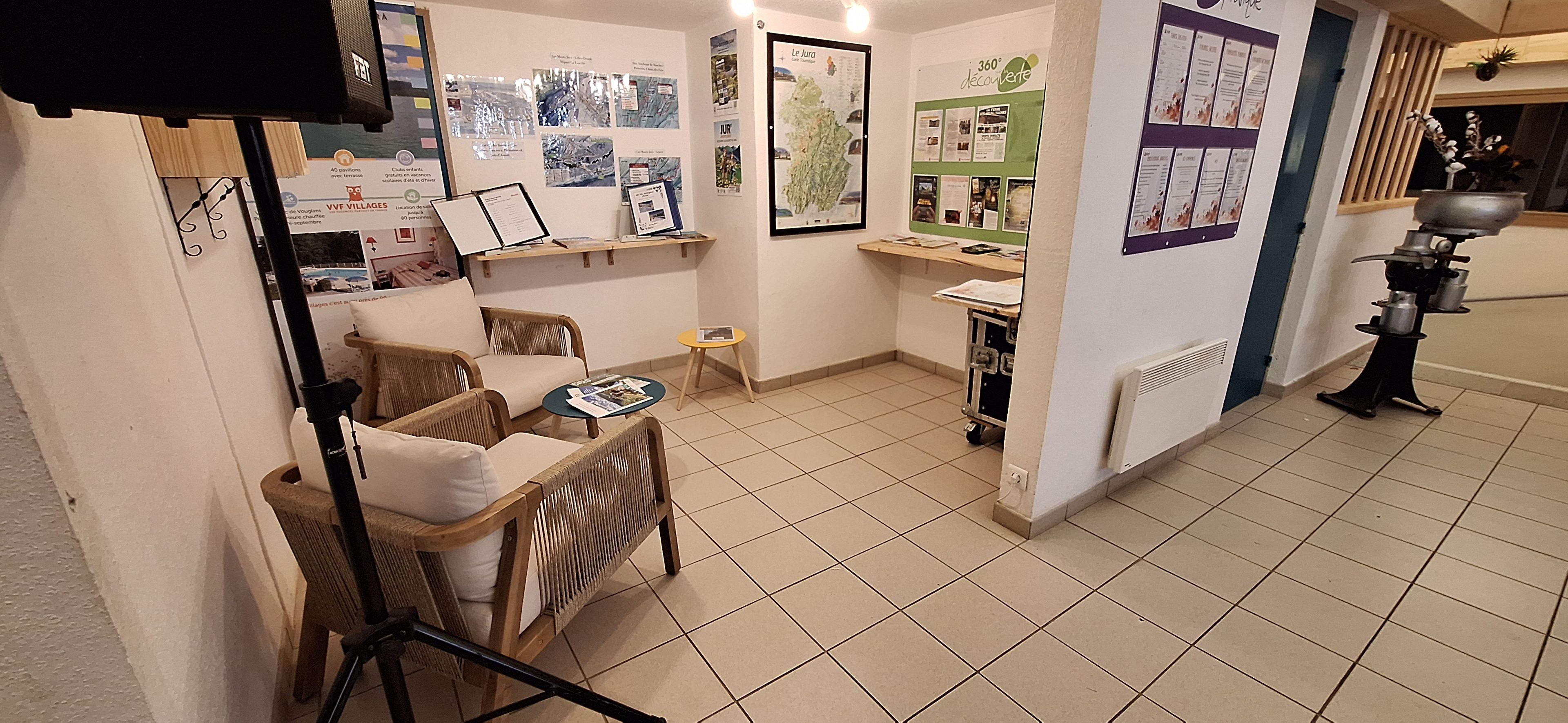 A room with wicker furniture, a small round table, a shelf with informational materials, and a radiator.