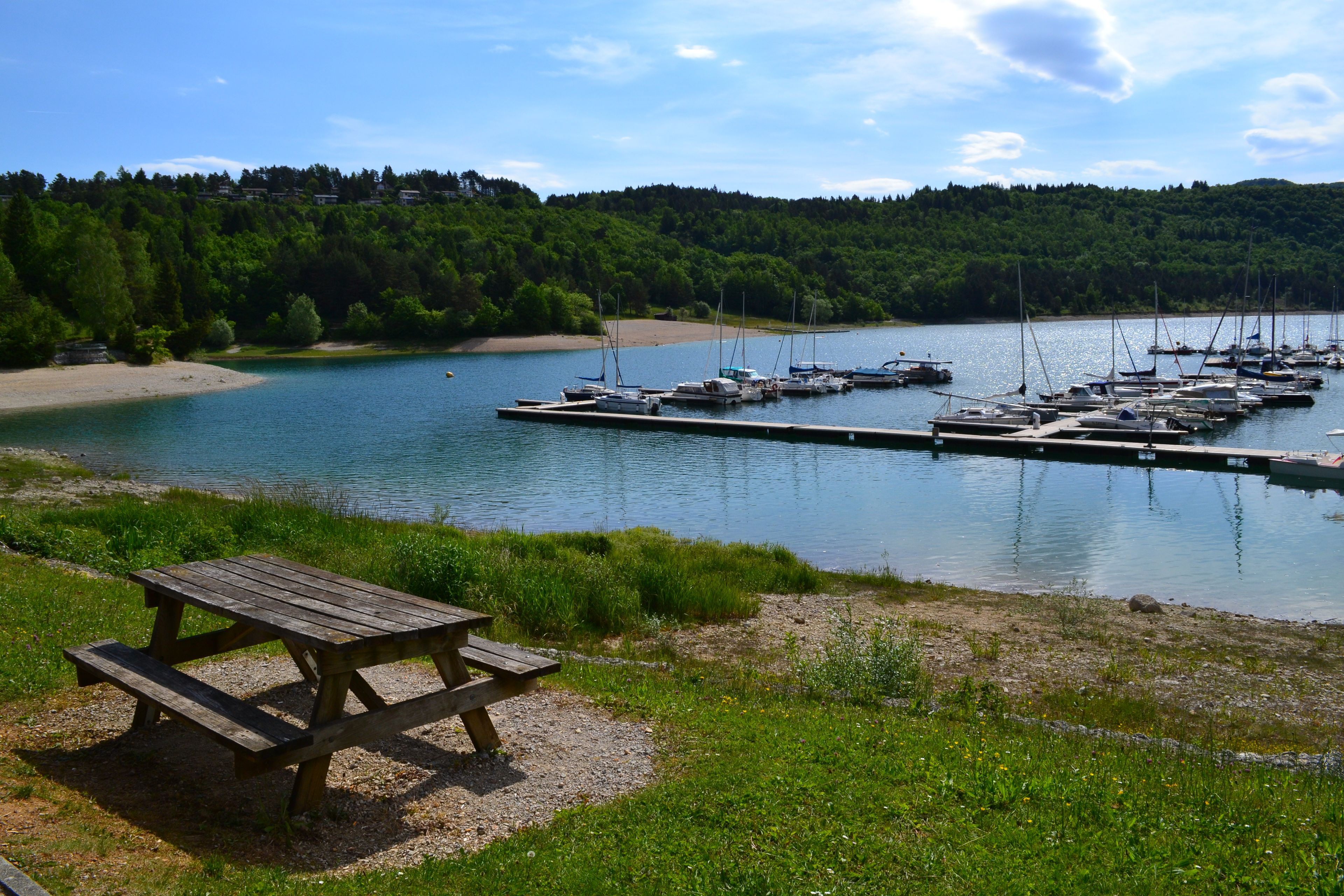 A lakeside view with a dock, boats, and a picnic table.