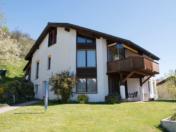 A two-story house with a balcony, a garden, and a clear sky. - Chasa Bainvgnü, (Scuol) by Interhome (Scuol)