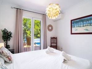 A hotel room with a bed, a chair, a potted plant, a painting, and a view of a pool and trees. - Aljamar 4A Burriana Beach by Casasol by Interhome (Nerja)