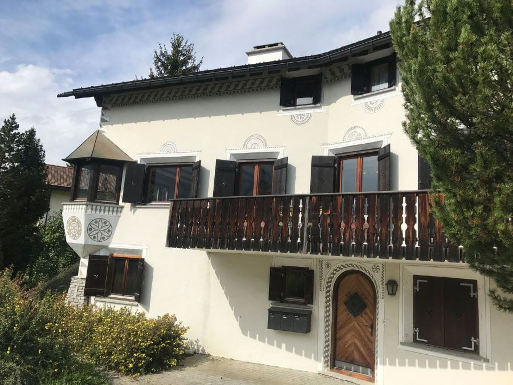 Ein zweistöckiges Gebäude mit Balkon, Holztür und einem Glockenturm.
