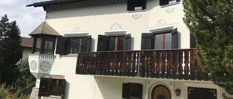 Ein zweistöckiges Gebäude mit Balkon, Holztür und einem Glockenturm.