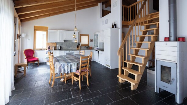Eine geräumige Küche mit Essbereich, einem roten Stuhl, einer Holztreppe und einem Kamin.