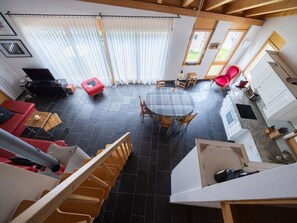 A spacious living area with a dining table, red sofa, and a staircase leading to an upper level. - Senda 517c, (Scuol) by Interhome (Scuol)