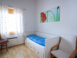 A room with a single bed, a chair, a radiator, and a painting on the wall. - Senda 517c, (Scuol) by Interhome (Scuol)