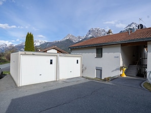 A two-story building with a garage, a staircase, and a mountain backdrop. - Senda 517c, (Scuol) by Interhome (Scuol)