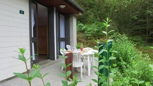 A small building with a door, a table with chairs, and a garden area with plants. - Vvf Villages Champs Sur Tarentaine (Champs-sur-Tarentaine-Marchal)