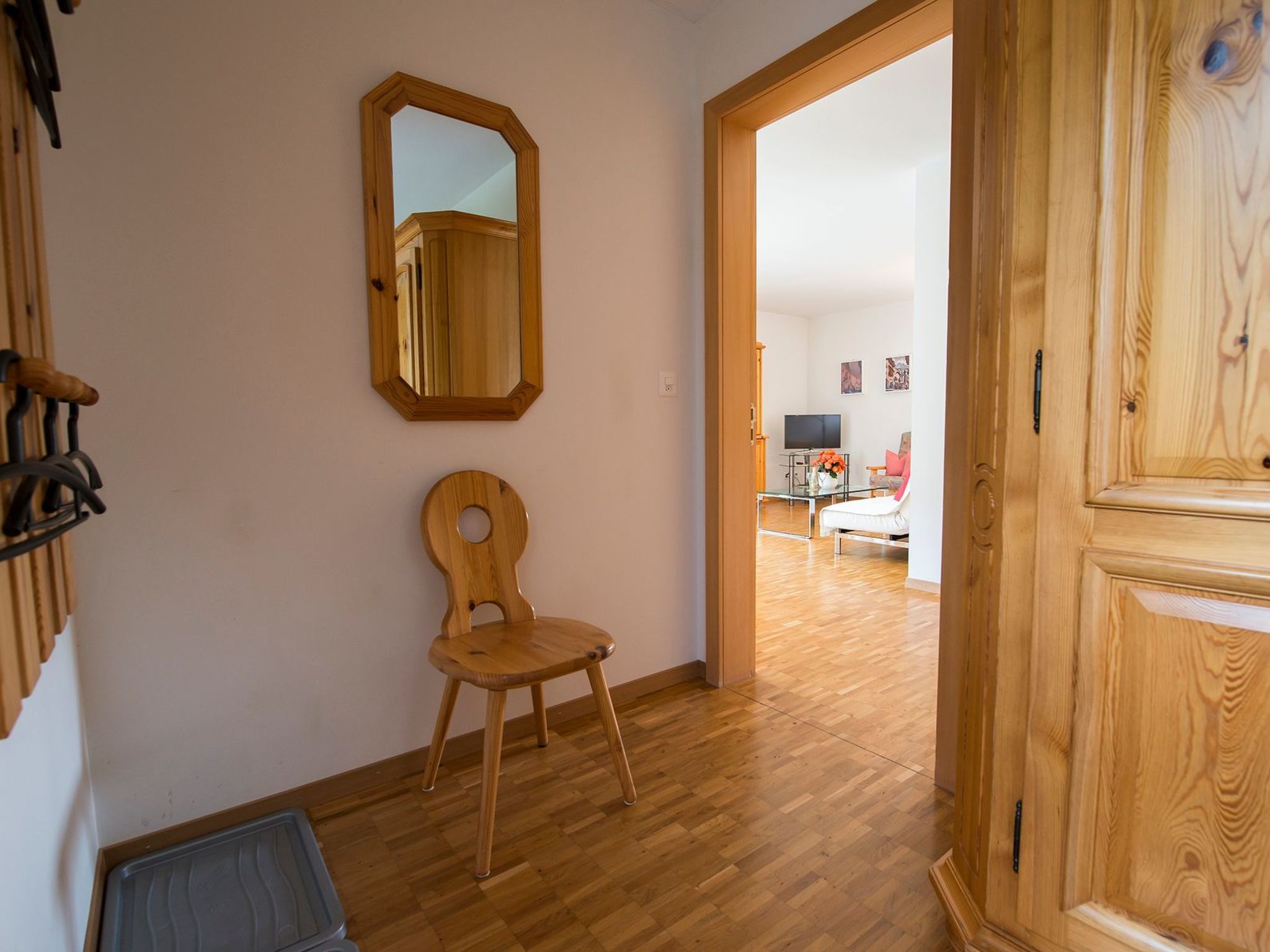 Ein Zimmer mit Holzboden, einem Holzstuhl, einem Spiegel und einer Holztür.