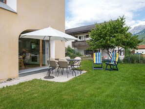 Un espace extérieur aménagé avec une table et des chaises, un coin salon abrité et une vue sur une montagne.