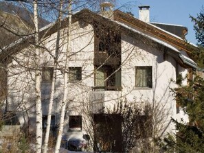 Ein zweistöckiges Gebäude mit geneigtem Dach, zahlreichen Fenstern und einem sichtbaren Schornstein.