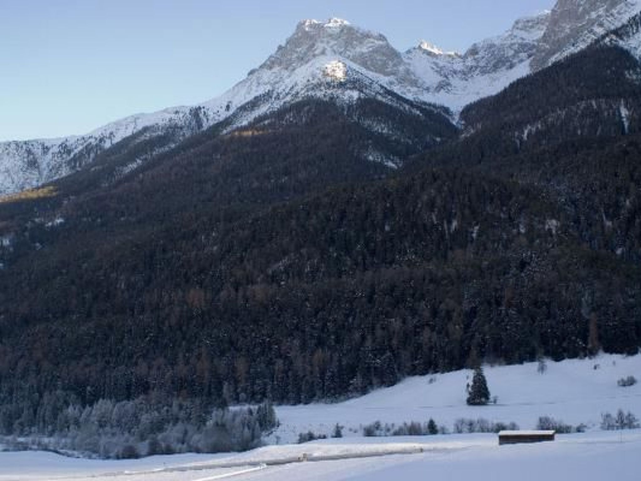 A mountainous landscape with snow-covered peaks and a clear sky.