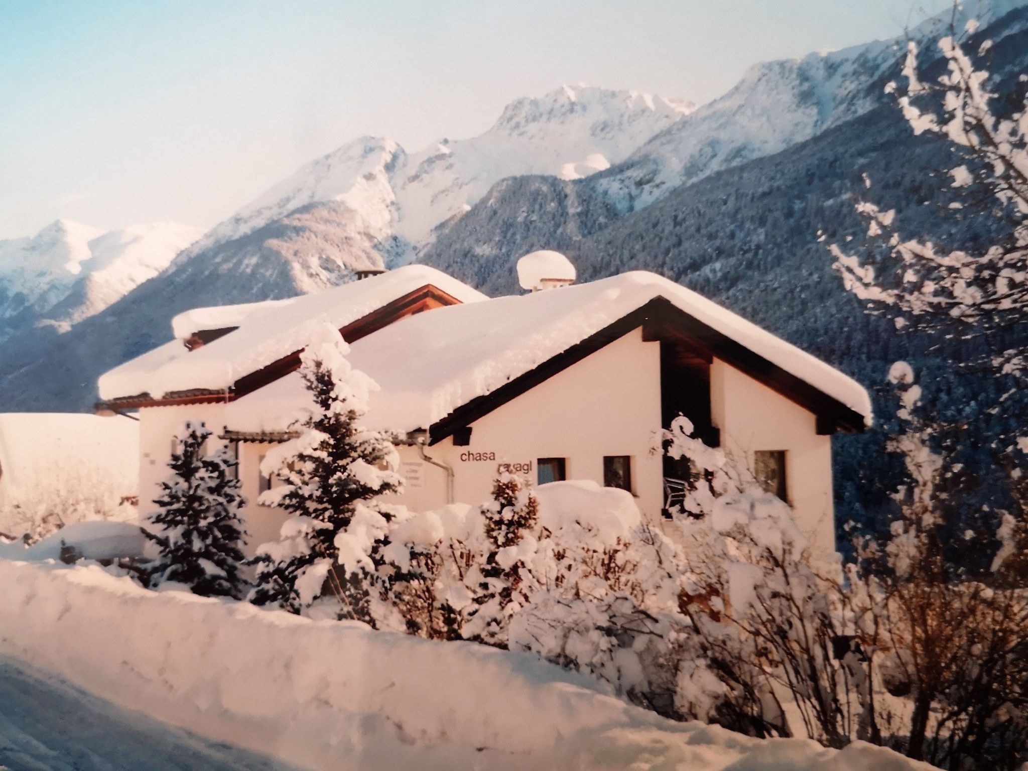 A snow-covered chalet with a mountain backdrop.