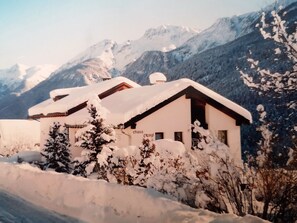 A snow-covered chalet with a mountain backdrop. - Chasa Ravagl, (Scuol) by Interhome (Scuol)