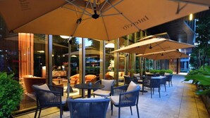 An outdoor seating area with tables and chairs, umbrellas, and a view of the interior of the building. - IntercityHotel Shanghai Hongqiao NECC (Shanghai)
