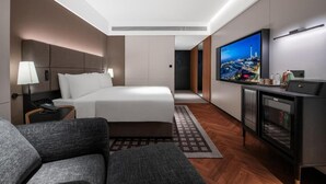 A modern hotel room with a large bed, a TV, a desk, and a view of a cityscape. - IntercityHotel Shanghai Hongqiao NECC (Shanghai)